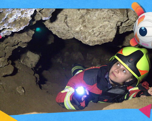 Frau in Feuerwehrausrüstung liegt in Felsspalte