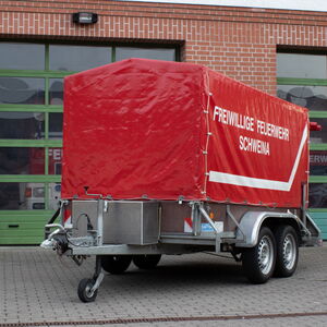 Materialanhänger der Feuerwehr steht vor Rolltoren eines Feuerwehrstützpunktes