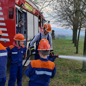 Kinder und Jugendliche bei der Feuerwehrausbildung mit Wasserspritze