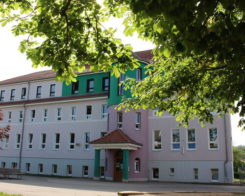 Grundschule Bad Liebenstein von außen, dreistöckiges Gebäude in Pastellfarben und Grün