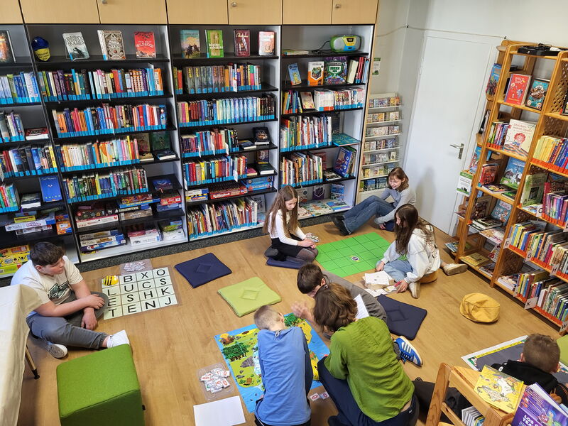 4 Bee-Bot Rätselstationen auf dem Fußboden einer Bibliothek. Kinder beschäftigen sich damit.