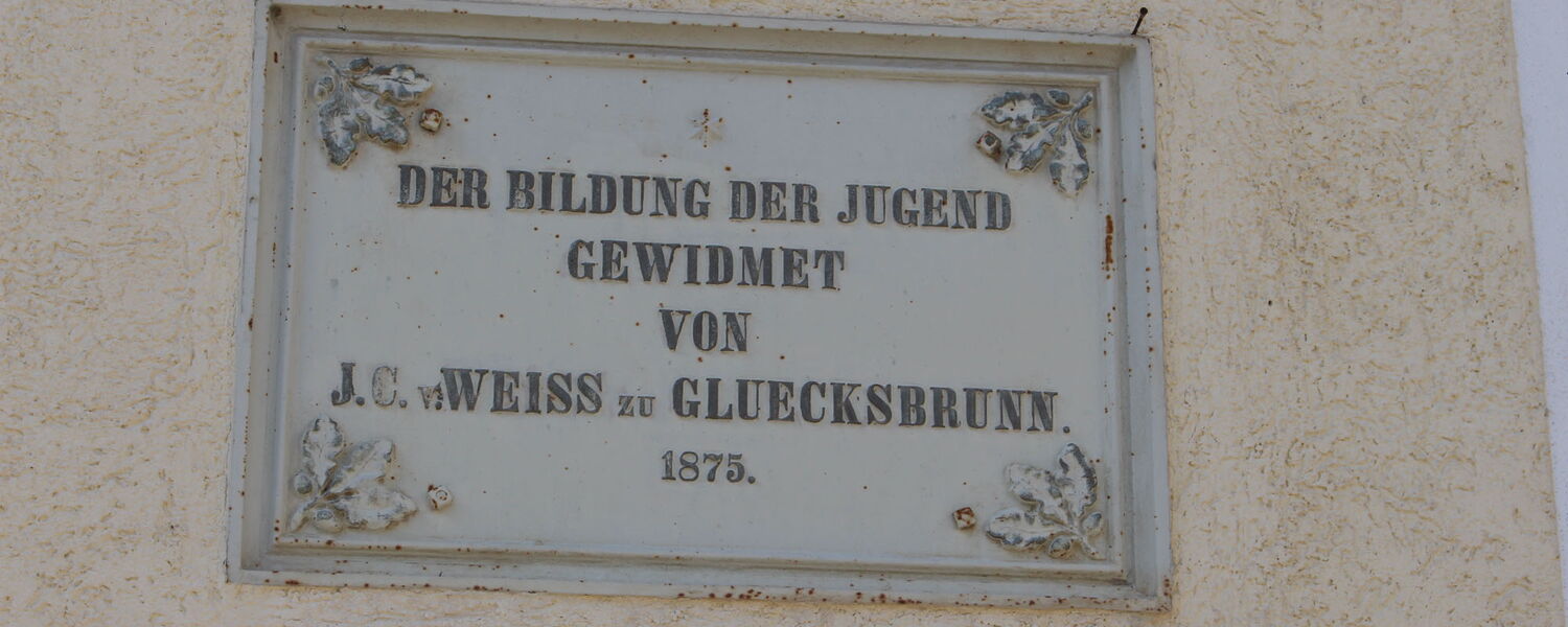 Historische Stifter-Tafel am Kindergarten Schweina, darauf steht: "Der Bildung der Jugend gewidmet von J.C.Weiss zu Glücksbrunn 1875"