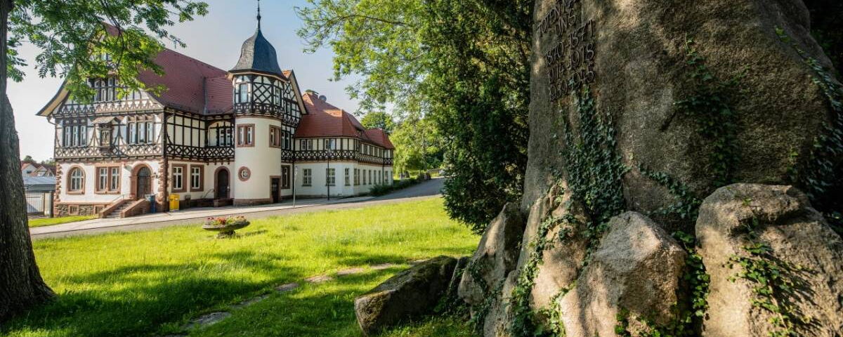 Landschaftsaufnahme mit Historischer Post und Kriegerdenkmal im Vordergrund