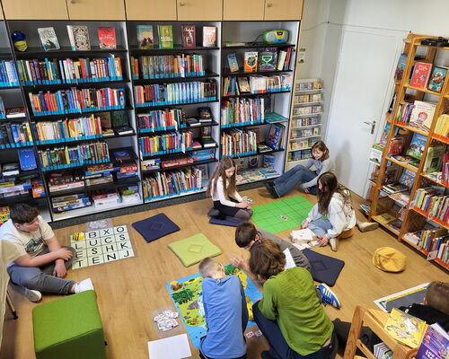 4 Bee-Bot Rätselstationen auf dem Fußboden einer Bibliothek. Kinder beschäftigen sich damit.