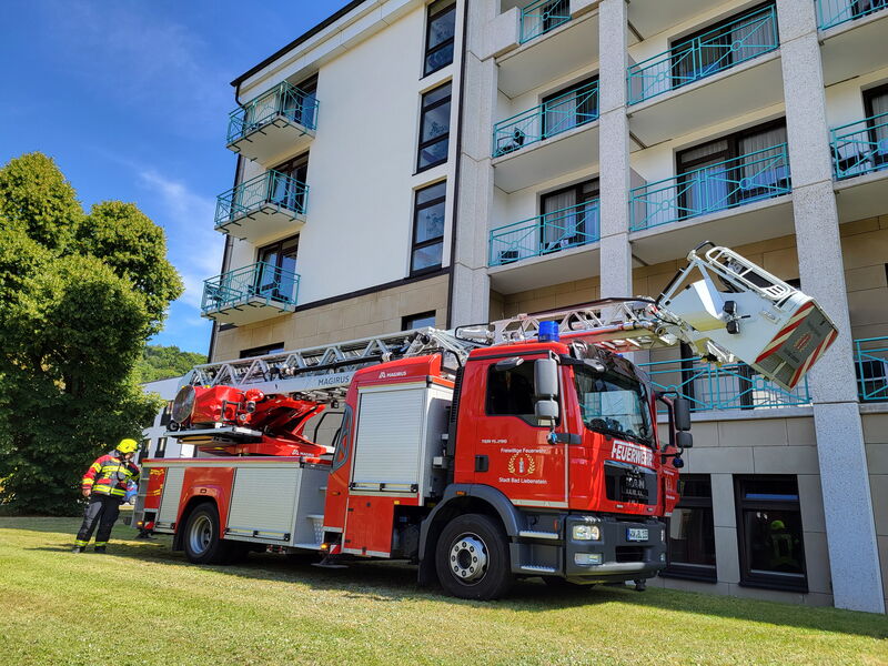 Feuerwehrauto mit Drehleiter steht auf Wiese vor mehrstöckigen Klinikgebäude