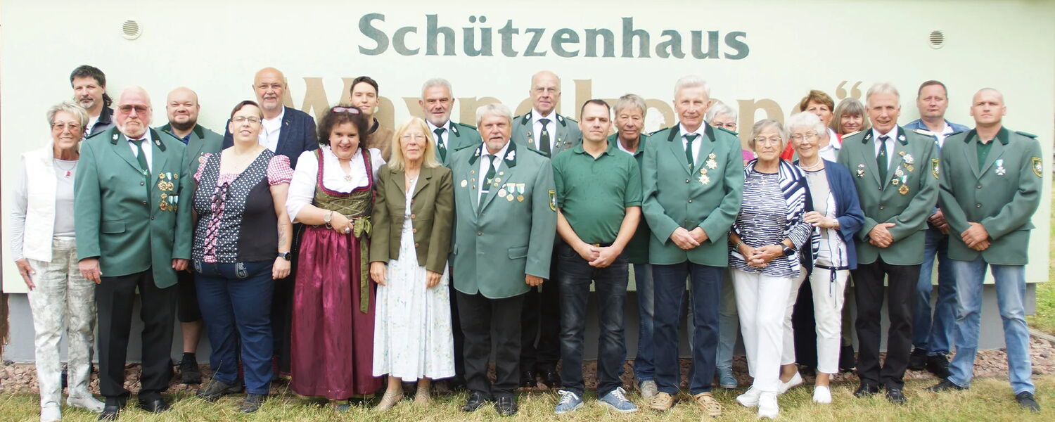 Gruppenfoto mit circa 25 Personen vor Schützenhauswand