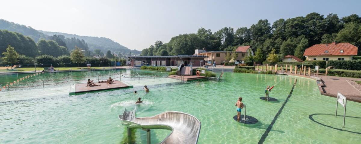 Aufnahme des Freibades BioBad Glücksbrunn mit Wasserrutsche, Wasserkanonen, und Liegeflächen