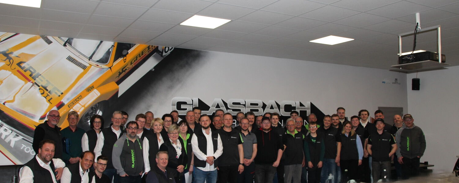 Gruppenfoto mit circa 50 Personen vor Glasbachwand