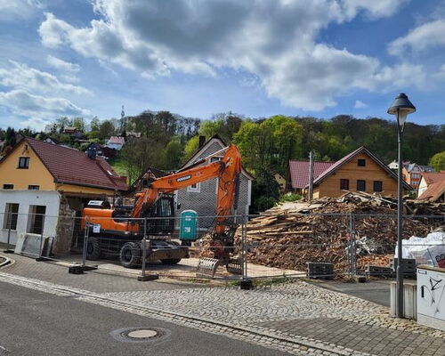 Räumbagger hinter Bauzaun und ein großer Schutthaufen am Hammerteich in Steinbach