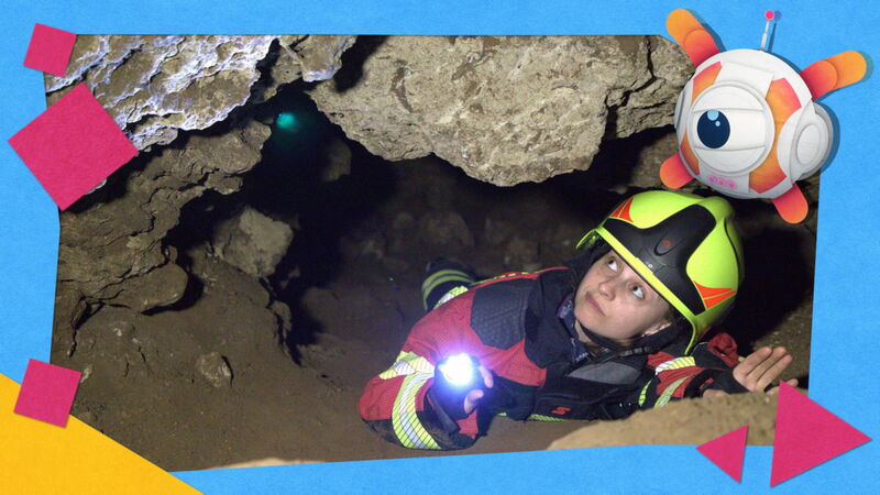 Frau in Feuerwehrausrüstung liegt in Felsspalte